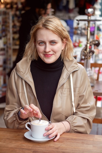 Koffie in straatcafé voor jonge lachende blanke vrouw