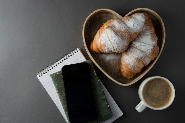 Koffie met croissant in houten hartvormige doos. Ruimte kopiëren.