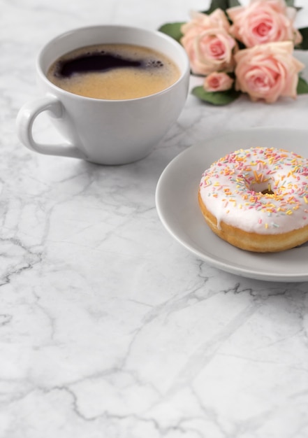 Koffie met kleurrijke doughnut in wit marmer