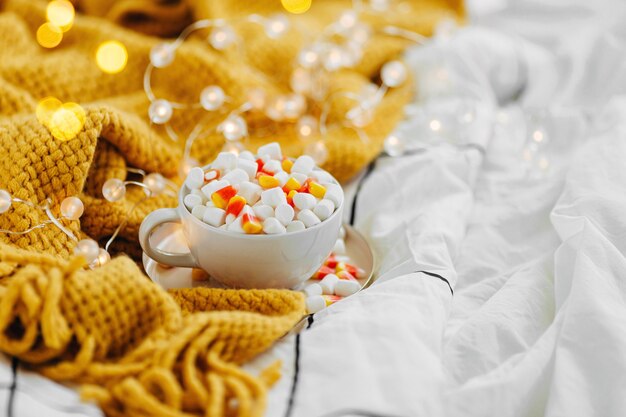 Koffie met marshmallow en snoepgraan op bed met warme plaid. Herfstdrankje, Ontbijt op bed. Hygge-concept.