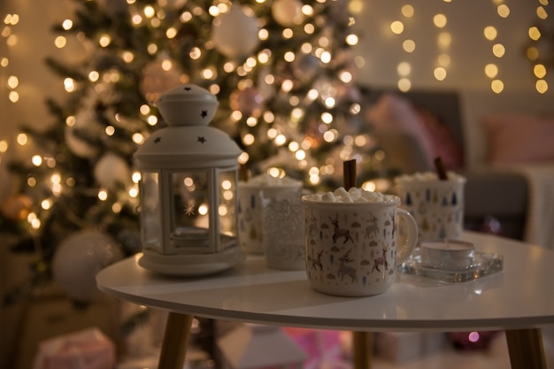 Foto koffie met marshmallow op tafel tegen de achtergrond van de kerstboom