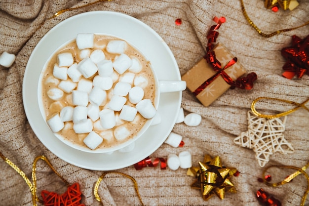 Koffie met marshmallows op een achtergrond van gebreide stof met geschenken en vakantiebogen