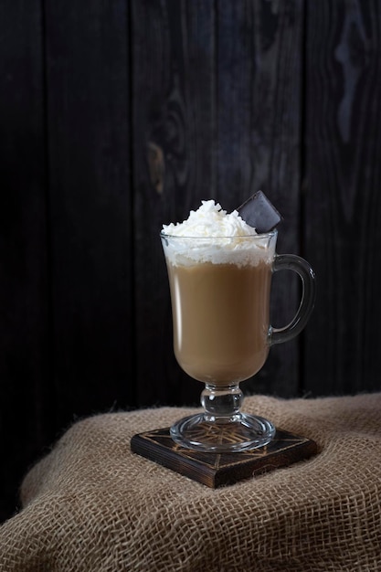 Koffie met melk met room en chocolade op een donkere houten ondergrond in rustieke stijl