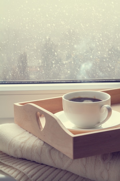 Koffie op dienblad en sweater binnen van de sneeuwende winter