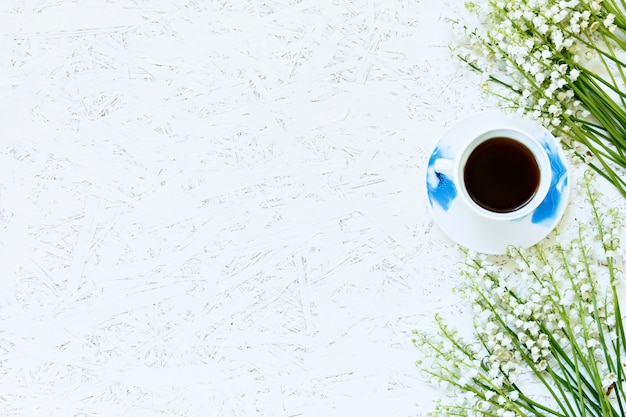 Koffie op een houten achtergrond en bloemen. Lelies van de vallei. De lente. Ochtend. 8 maart Vrouwendag