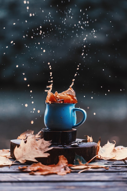 Foto koffie splash buiten. herfst samenstelling buiten. herfst. een kop warme koffie buiten.