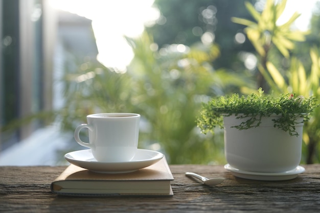 Foto koffiebeker en plant en notitieboek op houten tafel buiten