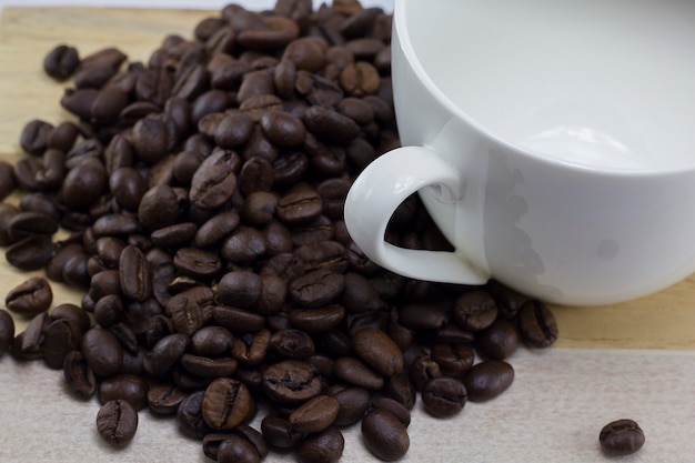 Koffiebonen en glas zijn wit op hout.