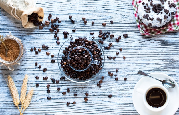 Koffiebonen en kopje koffie met andere componenten op verschillende houten oppervlak.