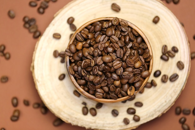 koffiebonen in een houten ronde beker op een deel van een boom op een bruine tafel. Koffiedrank.