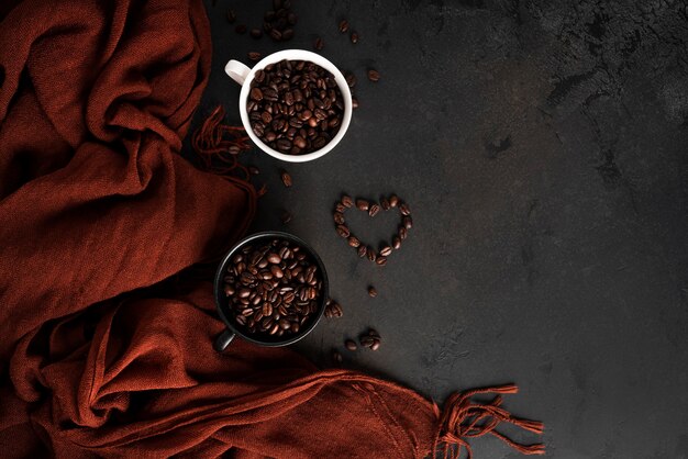 Koffiebonen in een kopje op een donkere achtergrond. Herfst, koffie samenstelling. Esdoornbladeren, bruine sjaal. Plat leggen. . Hoge kwaliteit foto