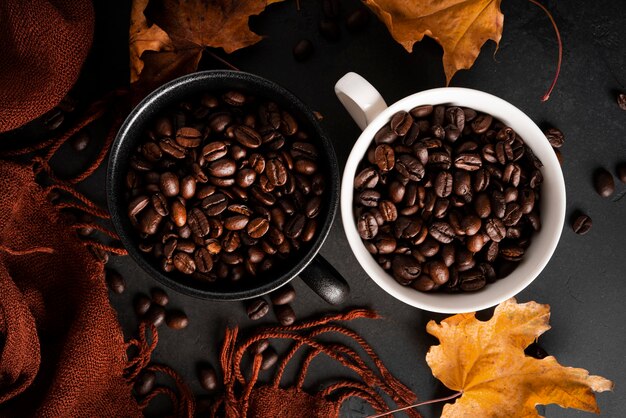 Koffiebonen in een kopje op een donkere achtergrond. Herfst, koffie samenstelling. Esdoornbladeren, bruine sjaal. Plat leggen. . Hoge kwaliteit foto