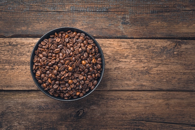 Koffiebonen in een zak en gemalen koffie in een kopje op een houten tafel met ruimte om te kopiëren. Bovenaanzicht, kopieer ruimte.