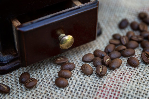 Koffiebonen met een houten koffiemolen op een jute. Bereiding van een aromatische drank. Detailopname.