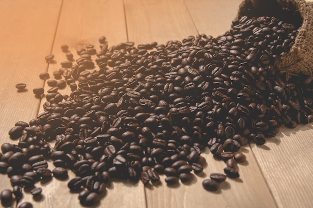 Koffiebonen met zakzak op houten lijstachtergrond.