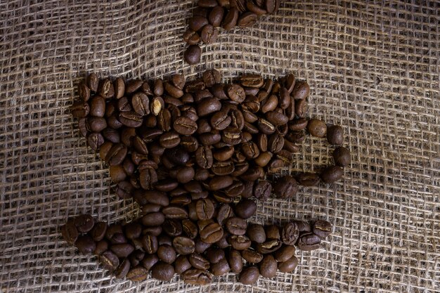 Koffiebonen neergelegd in de vorm van een kopje koffie op een ruwe jute