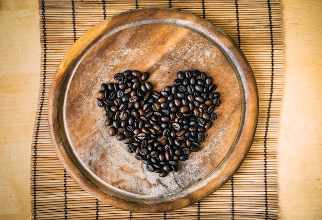 Koffiebonen op de houten snijplank in vorm hart