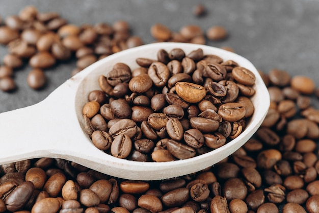 Koffiebonen op houten lepel geïsoleerd op donkere achtergrond