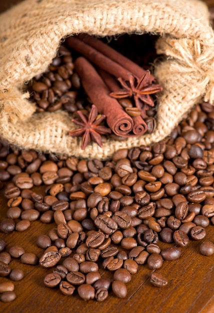 Koffiebonen, twee kaneelstokjes en anijssterren zijn verspreid over een houten tafel copyspace