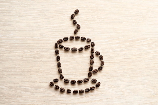 Koffieboonclose-up op een houten tafel Koffiebonen zijn neergelegd in de vorm van een kopje