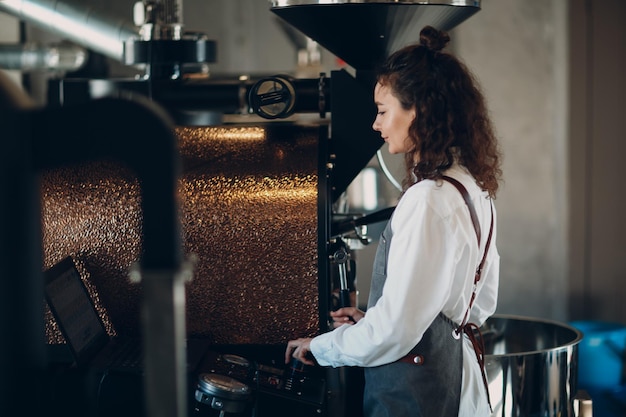 Koffiebrandermachine en barista-meisje regelen het koffiebrandproces