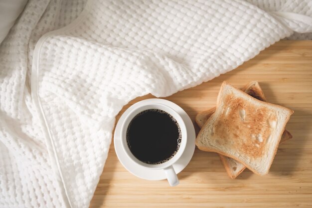 Koffiebrood in een witte kop die op het bed met geroosterd brood wordt geplaatst