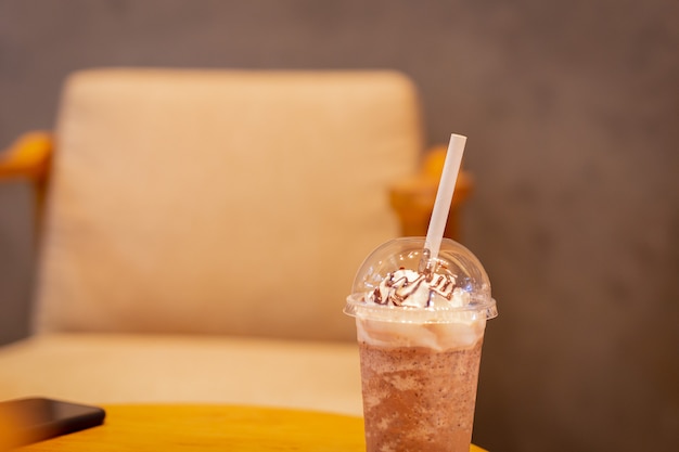 Koffiefrappuccino gemengd met papieren stro op houten tafel.