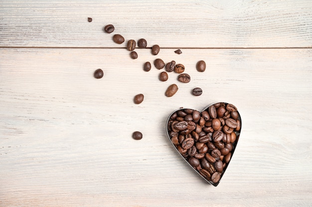 Koffiehart op een lichte achtergrond. Een vliegend hart met een staart van verspreide granen