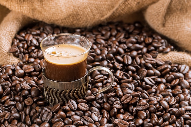 Koffiekop en koffiebonen op een houten lijst en zakachtergrond