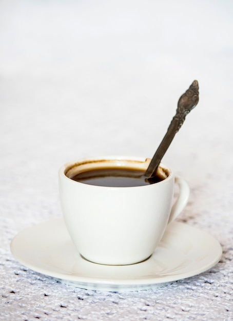 Koffiekop en schotel op een witte tafel.