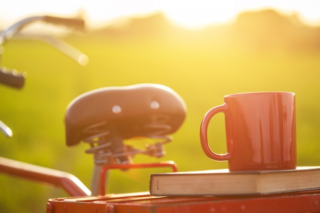 Koffiekop gezet op de rode de stijl klassieke fiets van japan bij mening van groen padieveld