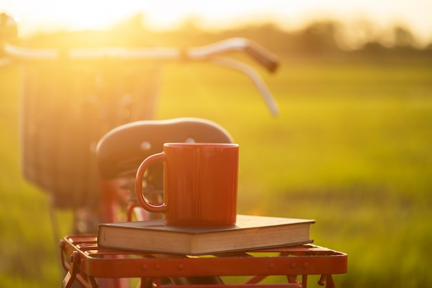 Koffiekop gezet op de Rode de stijl klassieke fiets van Japan bij mening van groen padieveld