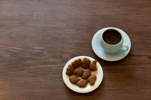 Koffiekop met chocoladekoekje op donkere houten achtergrond