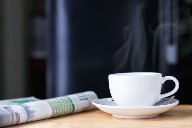 Koffiekop met krant op de houten lijst, zwarte achtergrond