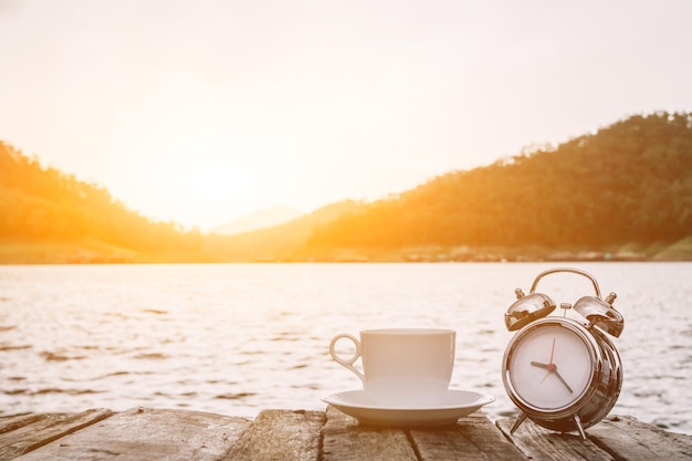 Koffiekop op tafel bij het meer tegen de hemel bij zonsondergang