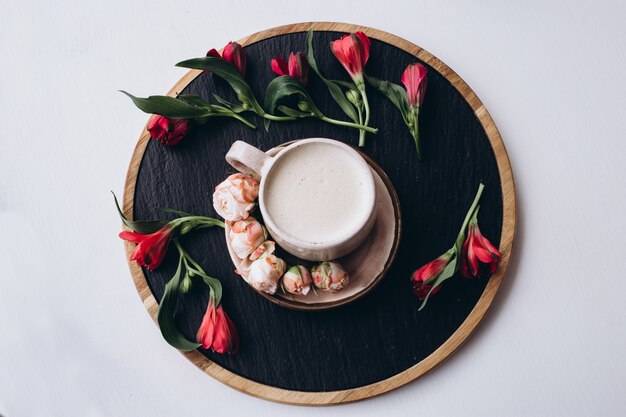 Koffiekopje en bloemen op donkere houten tafel in café