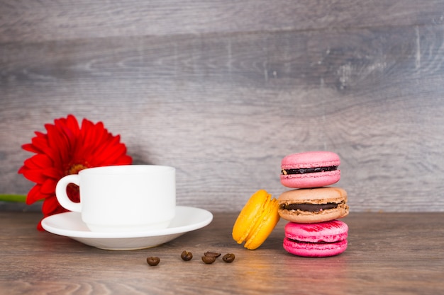 Koffiekopje en kleurrijke bitterkoekjes op houten tafel