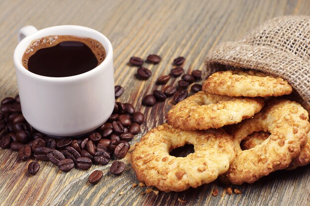 Koffiekopje en koekjes met noten in zak op oude houten tafel