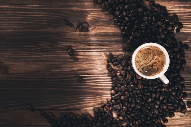 Koffiekopje en koffiebonen op houten achtergrond.