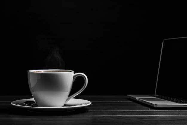 Koffiekopje en laptop op zwarte tafel