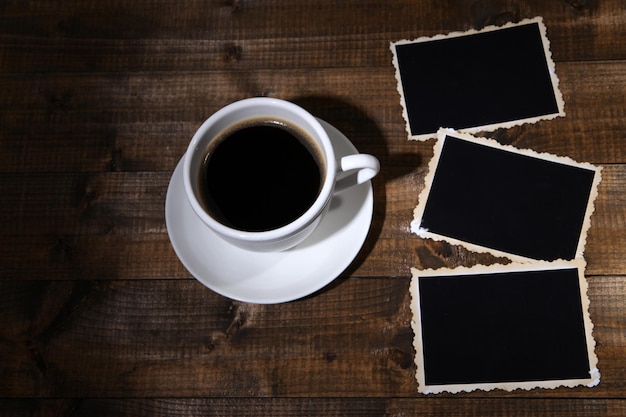 Koffiekopje en oude lege foto's op houten achtergrond