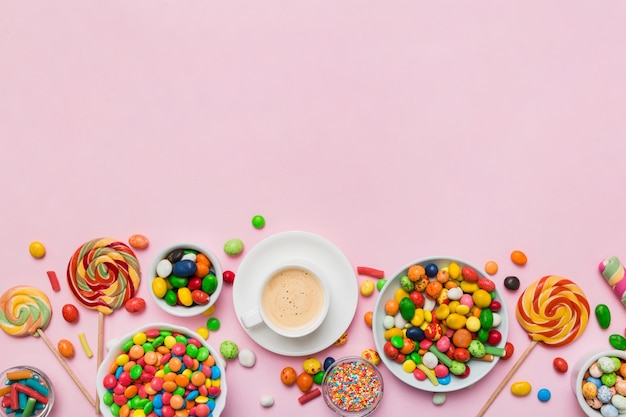 Koffiekopje met chocolaatjes en gekleurd snoep Bovenaanzicht op tabelachtergrond met kopieerruimte