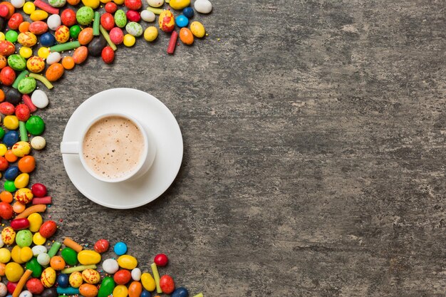 Koffiekopje met chocolaatjes en gekleurd snoep Bovenaanzicht op tabelachtergrond met kopieerruimte