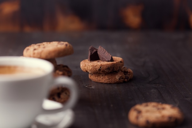 Koffiekopje met chocoladekoekjes op donkere oude houten tafel. Ontbijt