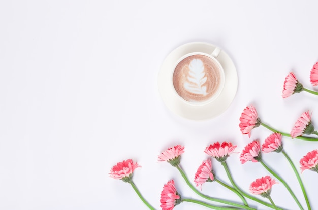 Koffiekopje met latte art met roze bloemen op witte achtergrond