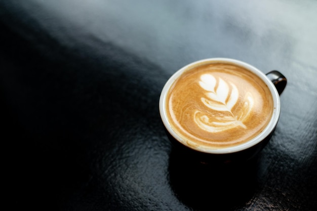 Koffiekopje met latte art op zwarte achtergrond