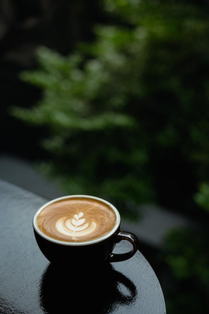 Koffiekopje met latte art op zwarte tafel in coffeeshop