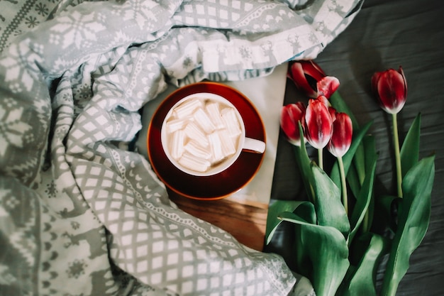 Koffiekopje met marshmallows en rode tulpen in bed. Concept van vakantie, verjaardag, Valentijnsdag, 8 maart