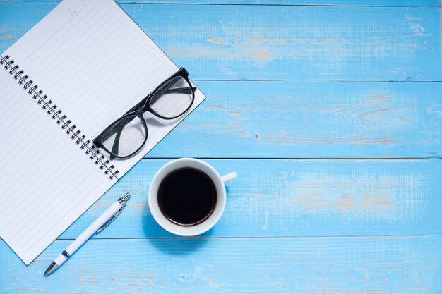 Koffiekopje met pen, notitieboekje en ogenglazen