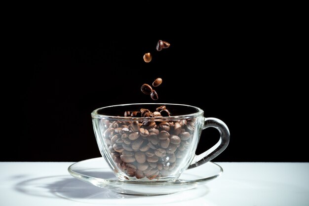 Koffiekopje met vallende bonen op zwarte achtergrond